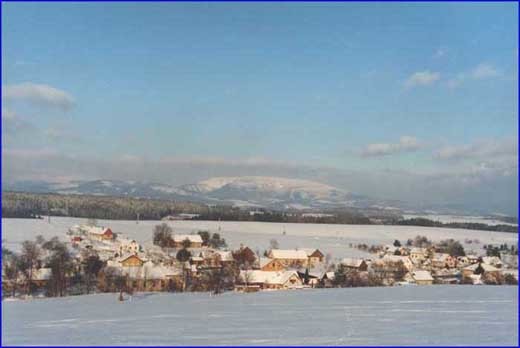 Zimní pohled na obec a panoráma Krkonoš